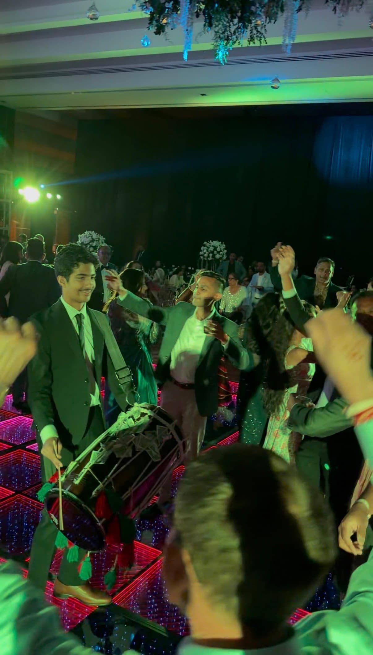 Ajisth performing dhol at an indoor wedding reception